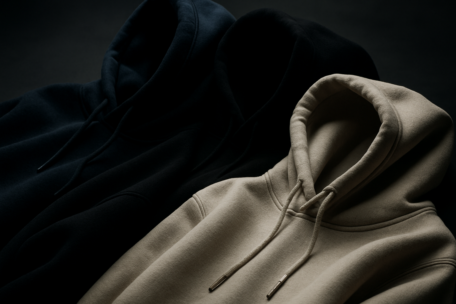 a cinematic detail shot on hoodie materials exploring premium fabric and comfort. Slow pace clips that showcase the navy, black white and beige hoodies. The background is in grey scale and there is dark lighting making it almost mysterious